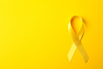 Yellow awareness ribbon on color background, space for text