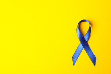 Blue awareness ribbon on yellow background, space for text