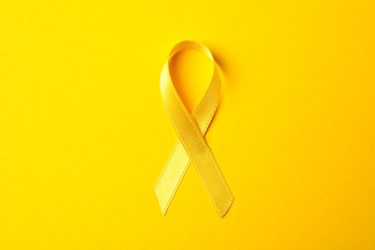 Yellow awareness ribbon on color background, space for text