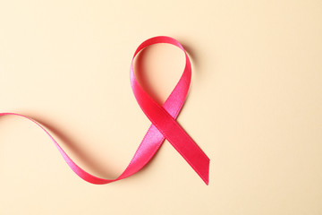 Pink awareness ribbon on color background, space for text