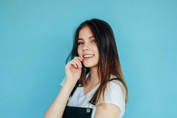 Happy carefree girl with dark long hair in white t-shirt isolated on blue background