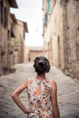 Young asian girl walking in Monticchiello town on summer day. Amazing promenade with traditional old stone houses - Tuscany, Italy, Europe