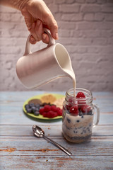 glass jug filled with cereals, raspberries and blueberries