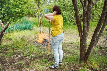 woman burns the grass in the village in the garden