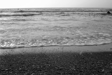 Obraz premium Black and white summer background of hot sand with sea or ocean wave bubbles with copy space for card or advertisement at dawn or sunset