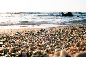 Summer background of hot sand with sea or ocean wave bubbles with copy space for card or advertisement at dawn or sunset
