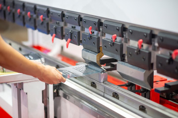 The skill operator working with the press machine. The sheet metal bending process with the...