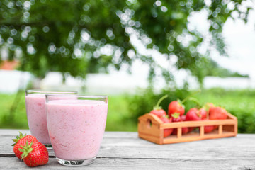 A glass of fresh cold smoothie with berries and cherrys on a wooden table, summer set, outdoor greed blured background,boke.