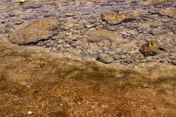 Summer background of hot sand with sea or ocean wave bubbles with copy space for card or advertisement at dawn or sunset