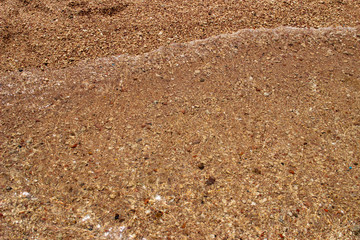 Summer background of hot sand with sea or ocean wave bubbles with copy space for card or advertisement at dawn or sunset