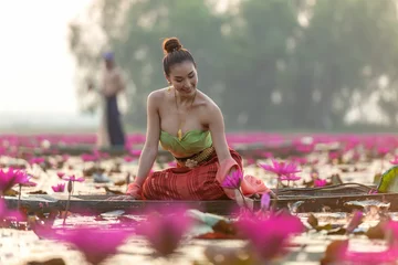 Poster Traditional asian woman harvest red lotus flower on the boat in nature river, fisherman background. Thailand © freebird7977