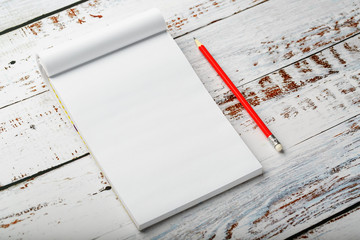 Notepad with a red pencil on a white wooden table against the background, for education, recording goals and deeds