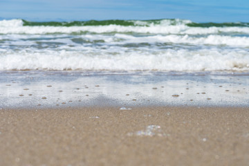 Seaside. A wave is coming. Small grains of sand close up. Concept. Background. Summer is over. Summer sales. Free space for text.