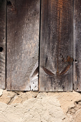 Old cob wall with cracked surface and old wooden boards