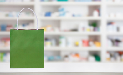 Paper bag on Pharmacy drugstore counter table with medicine and healthcare product on shelves blur...