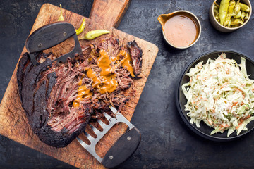 Traditional barbecue wagyu pulled beef with coleslaw and spicy sauce as top view on a rustic cutting board