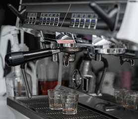 Coffee machine console.Stainless steel stainless steel machine close-up.The handle of the coffee machine is dripping coffee liquid.Transparent glass.This is the state of the coffee machine after work.