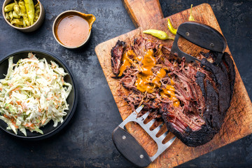 Traditional barbecue wagyu pulled beef with coleslaw and spicy sauce as top view on a rustic cutting board