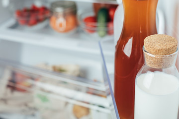 Open Refrigerator Filled with milk bottle, juice bottle and fresh fruits and vegetable.