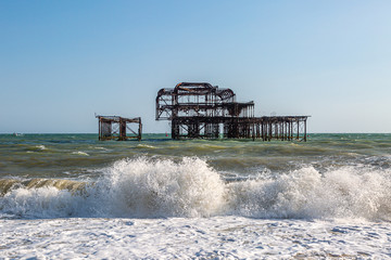 Waves crashing onto the beach in front of the iconic ruined West Pier in Brighton