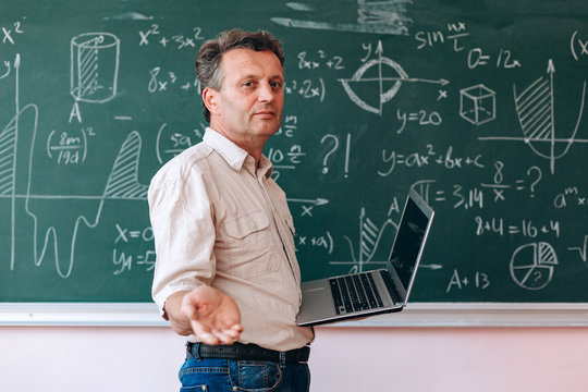 Teacher holding an open laptop and looking with smile at the camera.- Image
