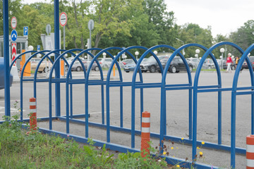 Fototapeta na wymiar Blue metal construction for bicycle parking. Parking for vehicles near the museum. Summer, cloudy day.
