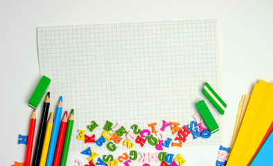 Fototapeta premium school supplies: multicolored wooden pencils, notebook, colored paper and blank white sheet in a check-box