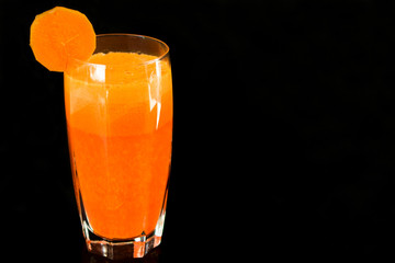  Fresh carrot juice in a glass is insulated against a black background. Copy space.