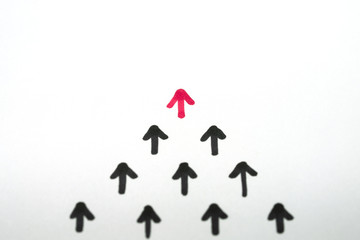 Leadership concept with red arrow leading among black arrows on white paper background