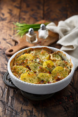 Homemade potato gratin with bacon and herbs