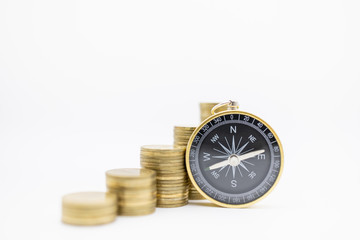 Succession, Finance, Business, Money, Security, Planning and Saving Concept. Close up of compass with stack of gold coins on white background and copy space.
