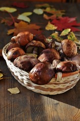 Forest mushrooms of the boletus (Leccinum) and autumn leaves on a wooden table. country style
