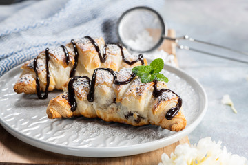 Delicious continental breakfast with fresh flaky french croissants and coffee, close up on the croissants. With white camellias flowers on a light background. Provence rustic style.