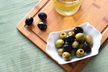 mixed olives on cutting board and olive oil, top view