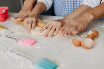 Obraz na płótnie Canvas Closeup female hands daughter and mother are stir the dough .- Image