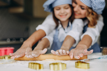 Little girl and mother  roll out the dough with a rolling pin together .- Image