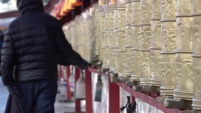 Tibetan pilgrims walk classic kora (circuit) around Potala Palace spinning traditional prayer wheels, religion and culture in Lhasa