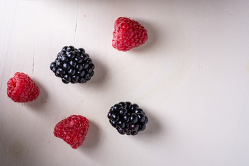 Raspberry and blackberry sweet organic juicy berries on white wooden table background, copy space