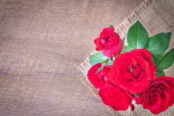 Flat lay of Beautiful rose red on sack and wooden table with , copy empty space.