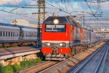 Fototapeta na wymiar Passenger train approaches to the station platform at summer evening time.