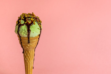funny creative concept with unstable pistachio ice cream cone with chocolate sauce and strewed nuts...