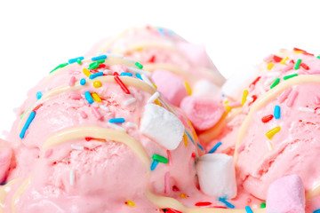 close up of pink strawberry scoops ice cream covered sprinkles, marshmallows and icing isolated on white background