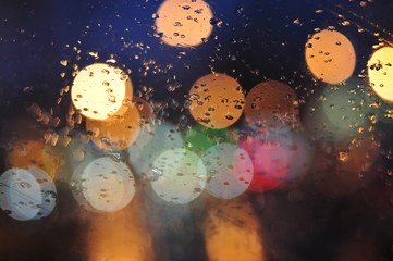 city lights through the car glass, selective focus, rain drops