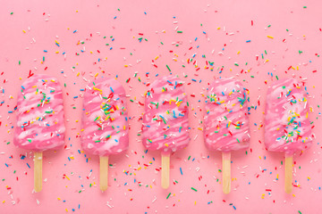 creative concept of popsicle with sprinkles and icing over festive pink background and space for...