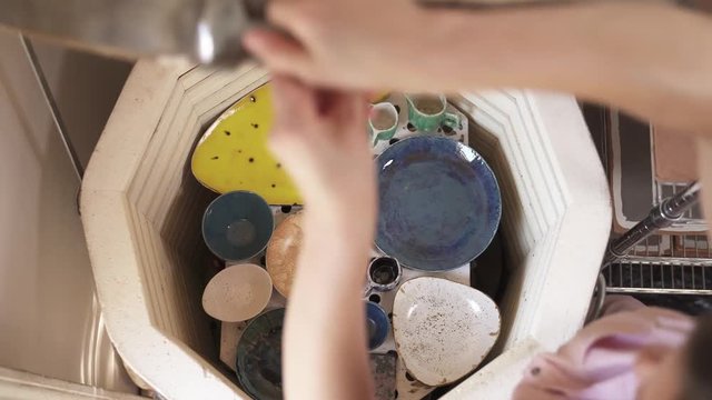 Oven for baking ceramics. Close-up of woman's hands opening the oven and taking out baked pottery plates. Ceramic dishes creation
