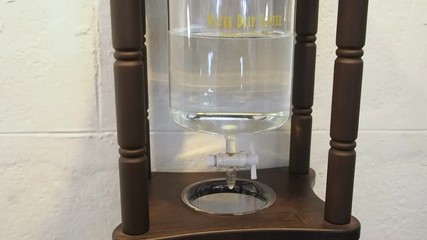 Professional Dutch cold brew maker dripper in process coffee make. Coffee brew making process: Water drips from a glass vessel into the hammers of coffee, seeping through it.