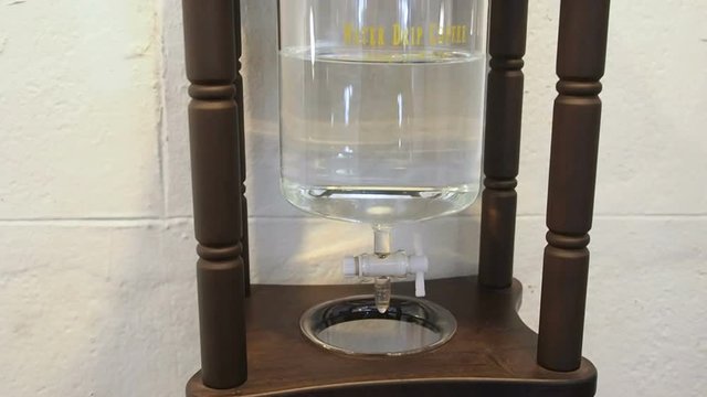 Professional Dutch cold brew maker dripper in process coffee make. Coffee brew making process: Water drips from a glass vessel into the hammers of coffee, seeping through it.