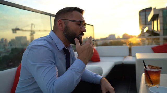 Businessman relaxing and smoking cigarette at luxury bar