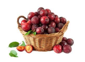 Ripe red plums with leafs in a basket on a white background.