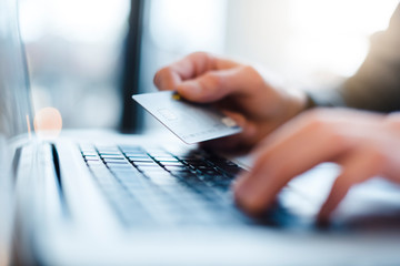 Man using laptop and holding credit card, close-up